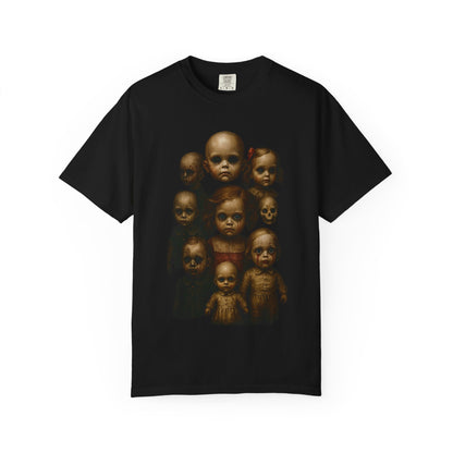 Black T-shirt featuring a grid of nine vintage-style haunted dolls with hollow eyes and distressed faces, arranged in a symmetrical pattern. The design evokes a gothic horror theme with eerie, unsettling visuals, perfect for fans of alternative fashion and creepy aesthetics.