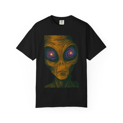 Black t-shirt featuring a surreal alien face with a textured orange complexion and large, galaxy-filled eyes in vibrant purple, pink, and blue tones; the design blends cosmic horror and psychedelic punk aesthetics.